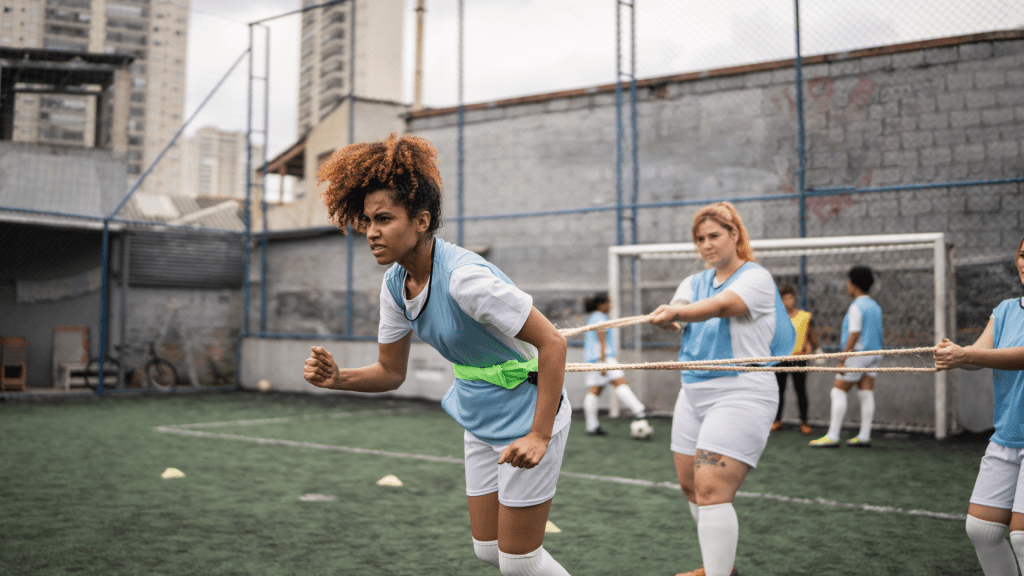 Zawodniczka piłki nożnej wykonująca sprint z oporem podczas treningu szybkości i mocy.