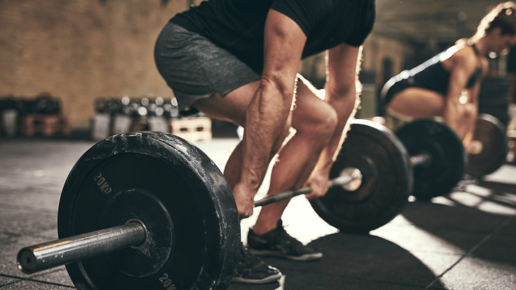 Piłkarz wykonujący martwy ciąg ze sztangą jako element treningu siłowego w przygotowaniu motorycznym.